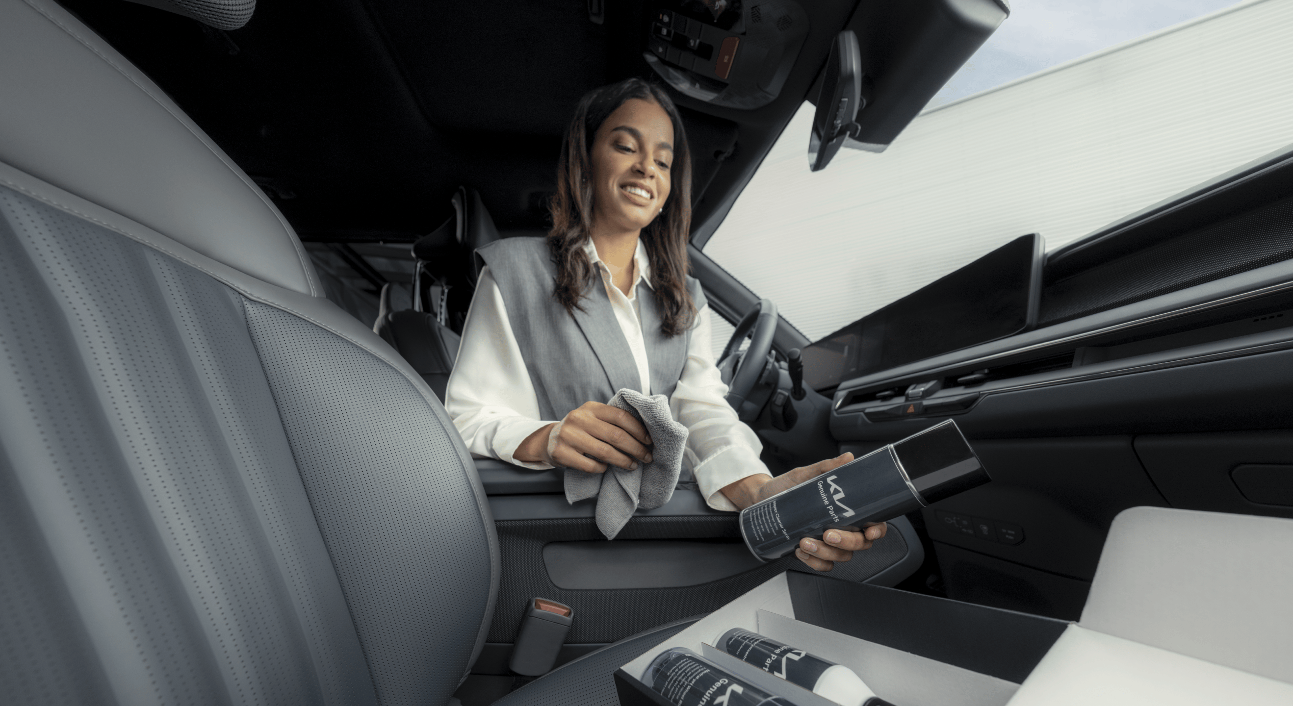 Eine Kia Besitzerin reinigt den Innenraum ihres Fahrzeugs mit dem Kia Originalteile Fahrzeugpflegeset.